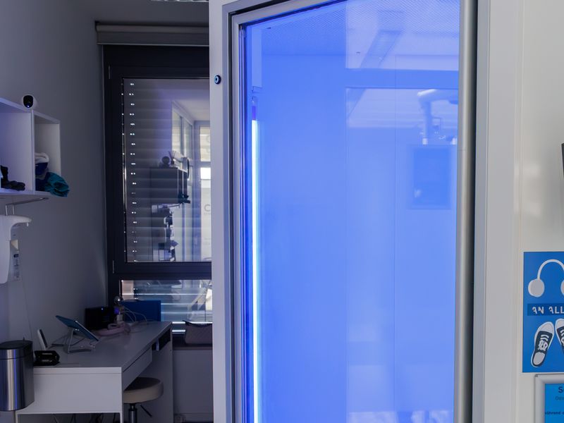 Eingang der Ganzkörper-Kältekammer des Partners CRYO°C mit blau leuchtender Glastür.