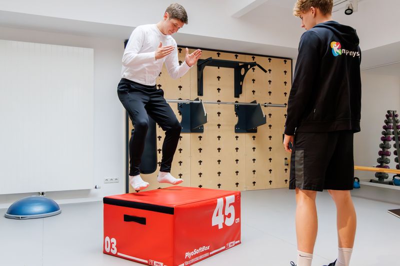 Patient landet auf einer Plyo-Box, der Therapeut beobachtet die Landung.