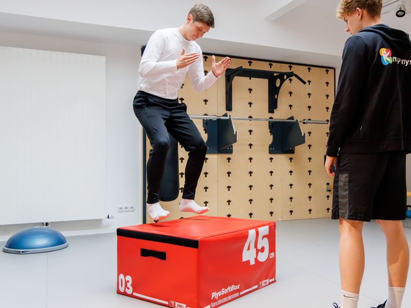 Patient landet auf einer Plyo-Box, der Therapeut beobachtet die Landung.