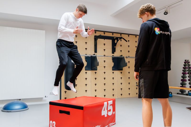 Patient springt auf eine Plyo-Box, ein Therapeut beobachtet den Sprung.