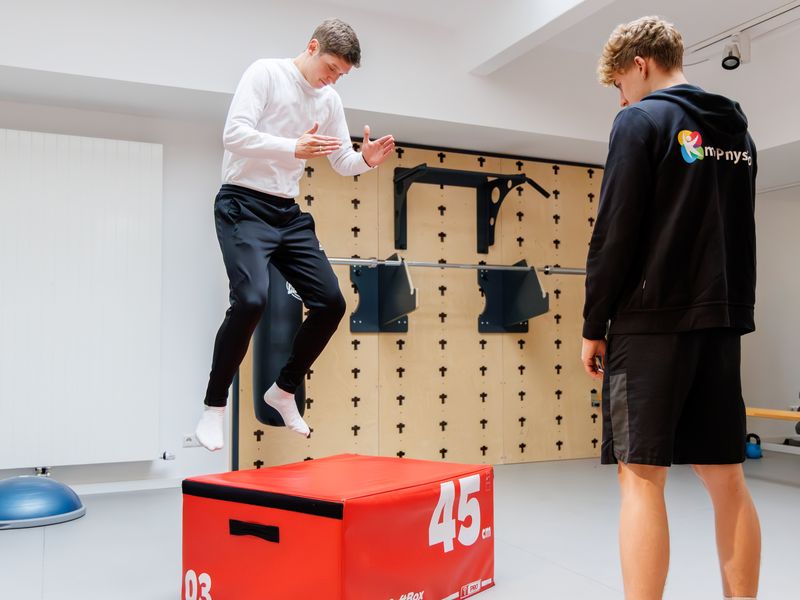 Patient springt auf eine Plyo-Box, ein Therapeut beobachtet den Sprung.