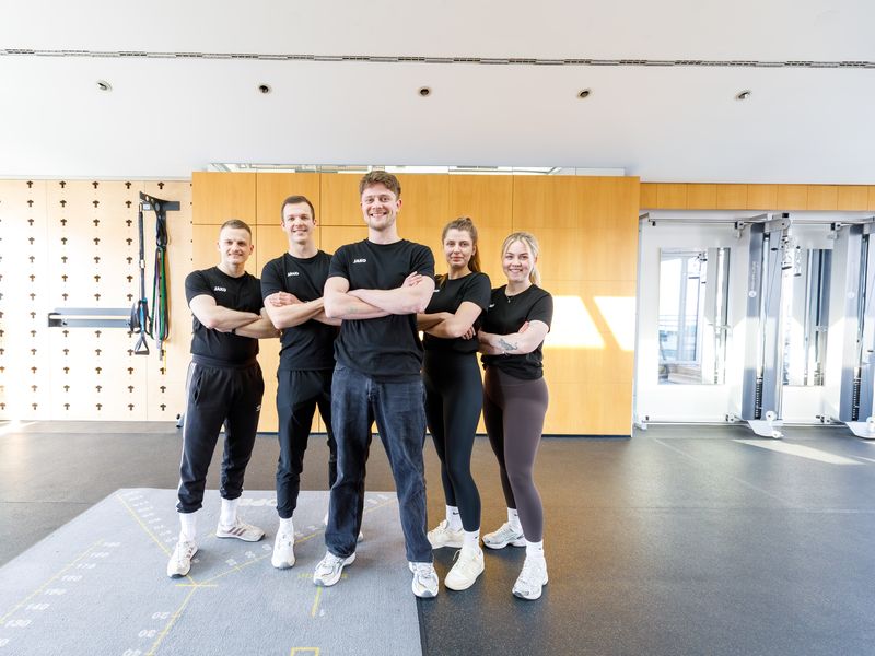 Fünf Mitarbeitende von myPhysio stehen mit verschränkten Armen nebeneinander in der Trainingsfläche.
